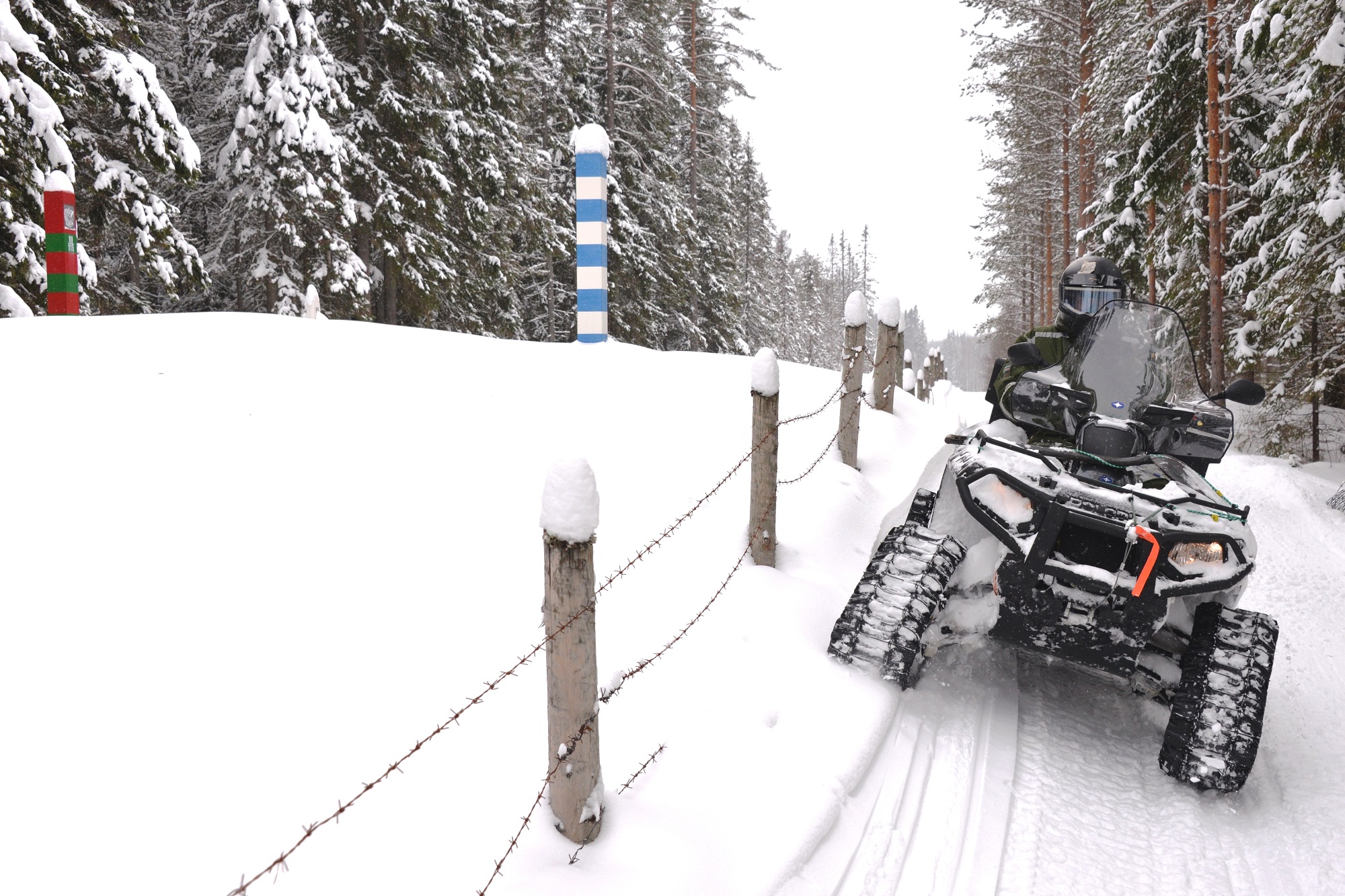 En traktorfyrhjuling med rullband i snön på patrulluppdrag i gränszonen.