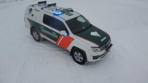 Pitkäperäinen maastopartioauto lumisessa maisemassa.